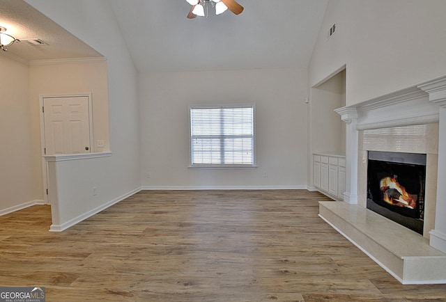 unfurnished living room with ceiling fan, a high end fireplace, vaulted ceiling, and light wood-type flooring