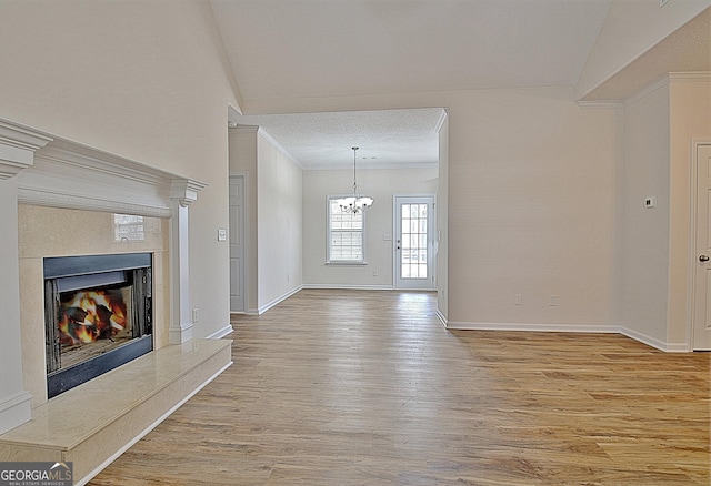 unfurnished living room with lofted ceiling, a premium fireplace, a textured ceiling, a notable chandelier, and wood-type flooring