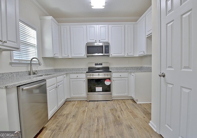 kitchen with light stone countertops, stainless steel appliances, crown molding, sink, and white cabinetry