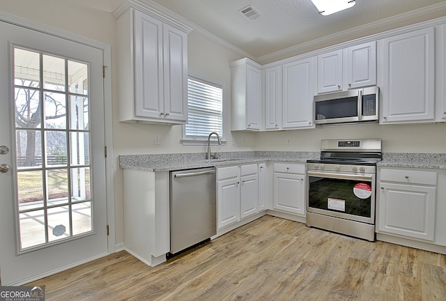 kitchen with white cabinetry, sink, light stone counters, light hardwood / wood-style flooring, and appliances with stainless steel finishes