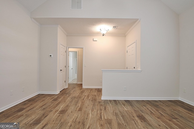 spare room with hardwood / wood-style floors, a textured ceiling, lofted ceiling, and ornamental molding