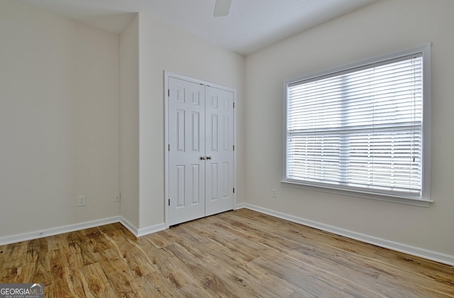 unfurnished bedroom with ceiling fan, light wood-type flooring, and a closet