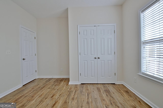 unfurnished bedroom with a closet and light hardwood / wood-style floors