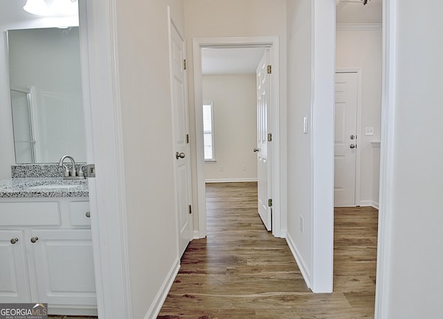 hall featuring light wood-type flooring, crown molding, and sink