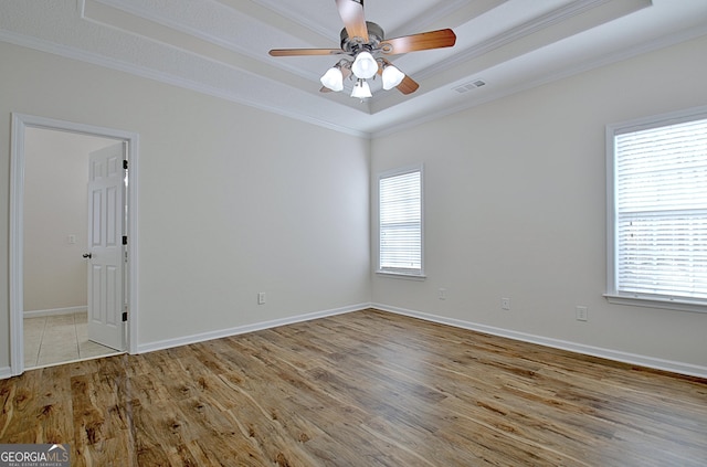 unfurnished room featuring ornamental molding, a tray ceiling, ceiling fan, and light hardwood / wood-style floors