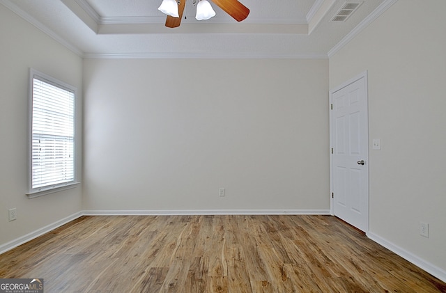 unfurnished room featuring ceiling fan, light hardwood / wood-style floors, a raised ceiling, and a wealth of natural light