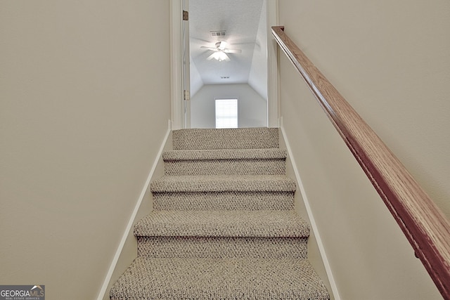 stairway with a textured ceiling, ceiling fan, and vaulted ceiling