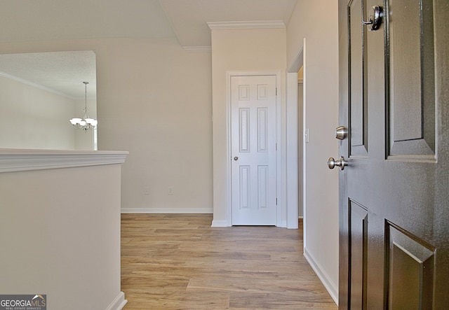 hall with crown molding, light hardwood / wood-style floors, and a notable chandelier