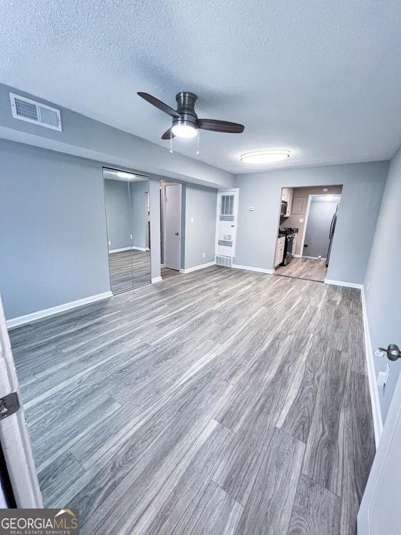 unfurnished living room with ceiling fan, a textured ceiling, and hardwood / wood-style flooring