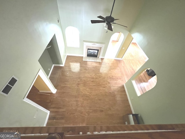 unfurnished living room with ceiling fan, a fireplace, and a high ceiling