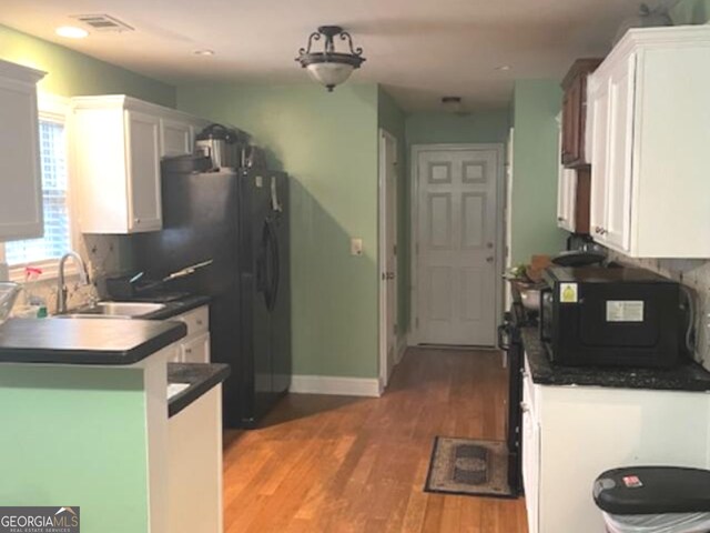 kitchen featuring kitchen peninsula, hardwood / wood-style floors, white cabinetry, and sink