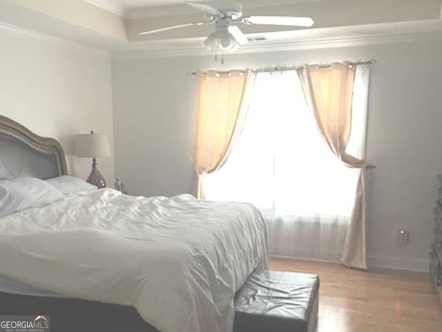 bedroom with hardwood / wood-style floors, ceiling fan, crown molding, and multiple windows