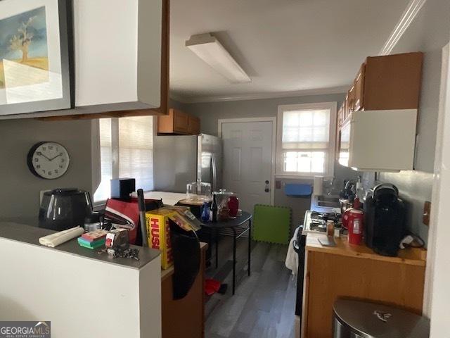 kitchen featuring range, stainless steel fridge, hardwood / wood-style floors, and ornamental molding