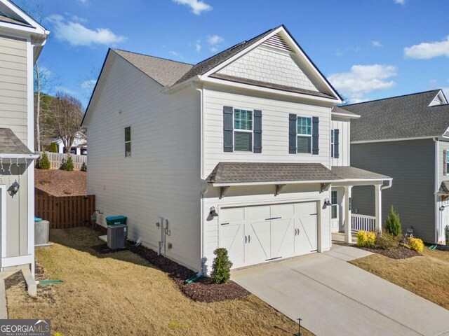 front facade with central AC, a garage, and a front lawn