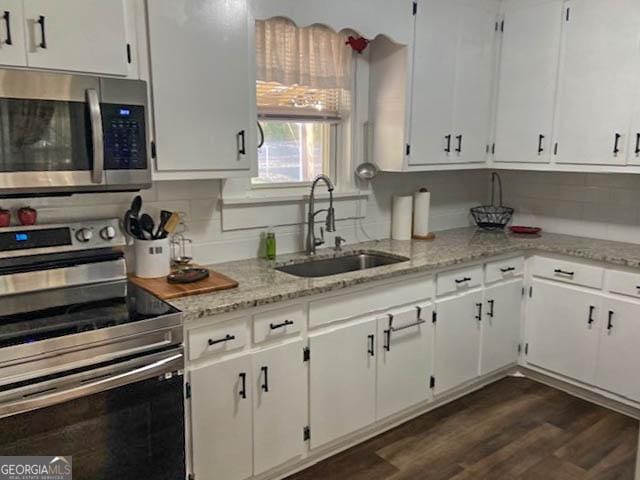 kitchen with dark hardwood / wood-style floors, white cabinetry, sink, backsplash, and stainless steel appliances