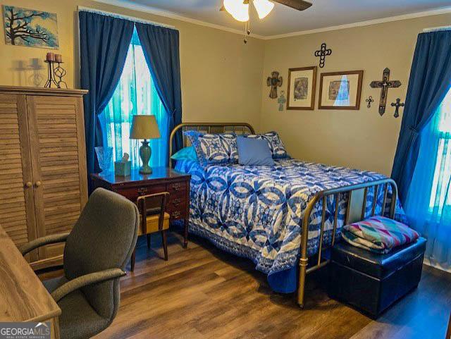 bedroom with crown molding, ceiling fan, and hardwood / wood-style floors