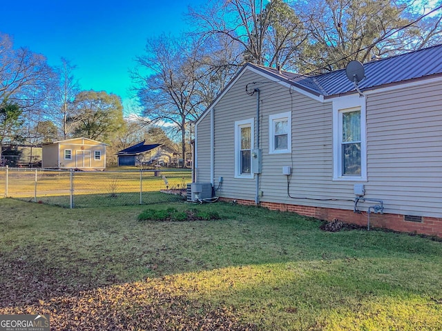 view of side of property featuring a yard and central AC