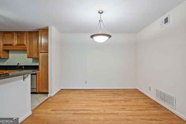 kitchen with decorative backsplash, light hardwood / wood-style floors, and hanging light fixtures