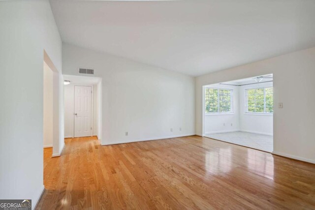 unfurnished room featuring light hardwood / wood-style floors and vaulted ceiling