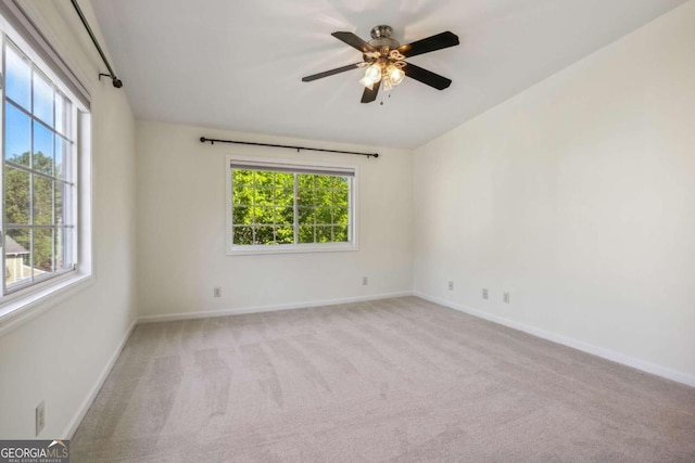 unfurnished room featuring ceiling fan, plenty of natural light, and light colored carpet