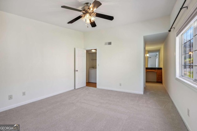 unfurnished bedroom with washer / clothes dryer, light carpet, and ceiling fan