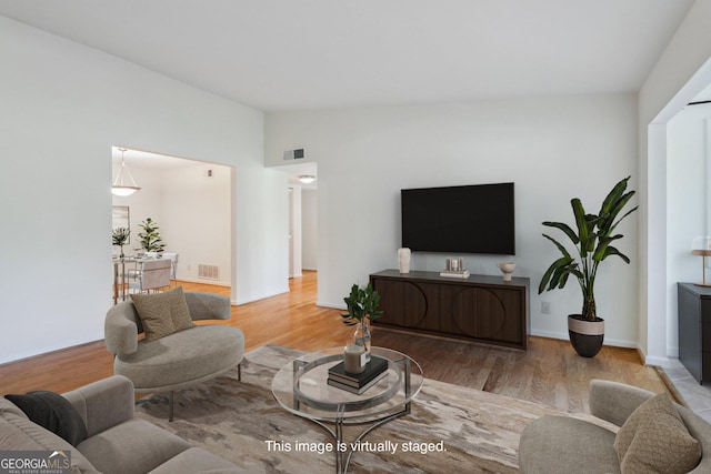 living room with light wood-type flooring and vaulted ceiling