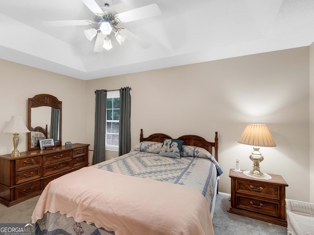 bedroom featuring ceiling fan, light carpet, and a tray ceiling