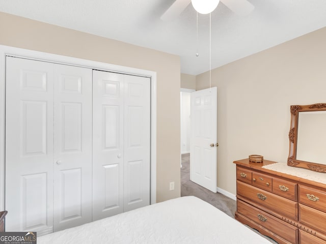 bedroom featuring ceiling fan, a closet, and dark colored carpet