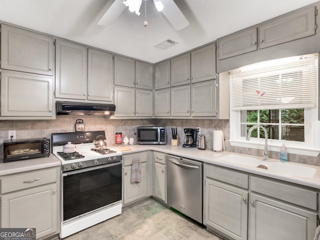 kitchen with gray cabinetry, a textured ceiling, stainless steel appliances, ceiling fan, and sink