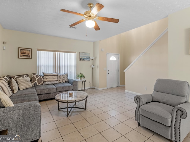 living room with ceiling fan, light tile patterned floors, and a textured ceiling