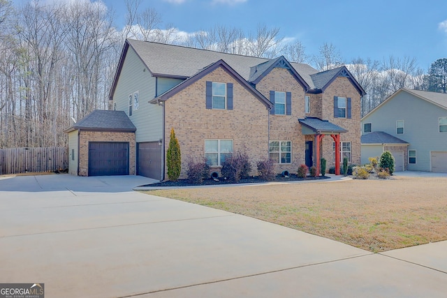 traditional-style house with brick siding, an attached garage, fence, driveway, and a front lawn