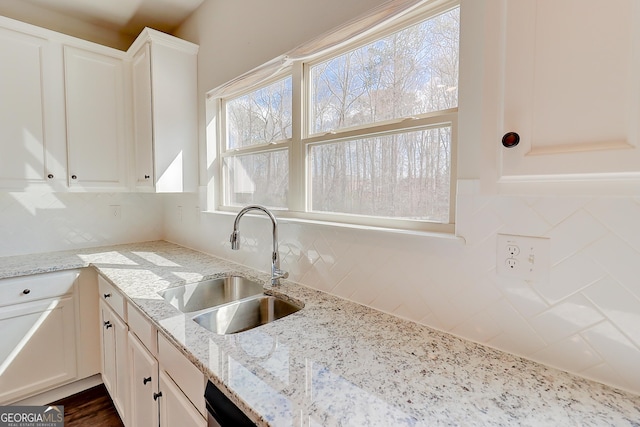 kitchen with a sink, white cabinetry, and light stone countertops