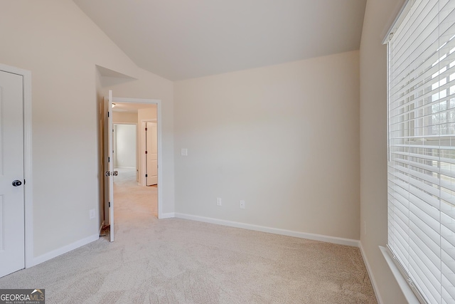 unfurnished bedroom with light carpet, vaulted ceiling, and baseboards