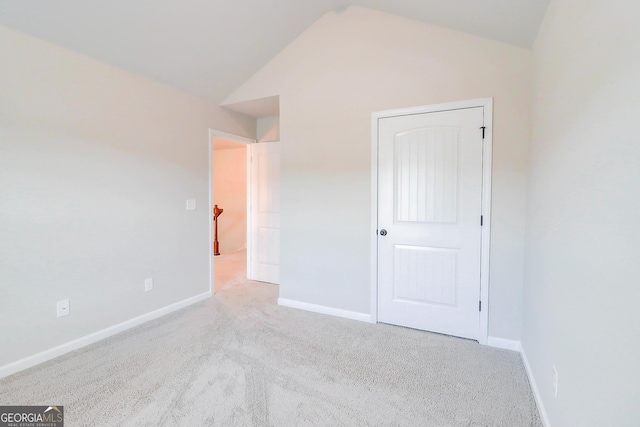 unfurnished bedroom with lofted ceiling, light carpet, and baseboards