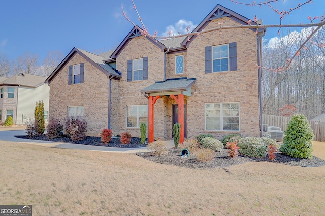 traditional-style home with brick siding, a front lawn, and fence