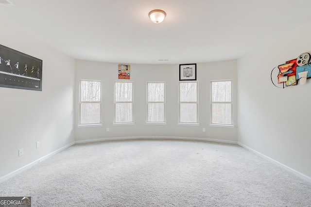 unfurnished room with light carpet, baseboards, and a wealth of natural light