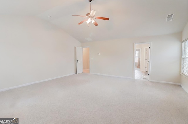 empty room featuring light colored carpet, visible vents, lofted ceiling, and baseboards