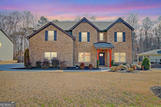 traditional home with brick siding and a front lawn