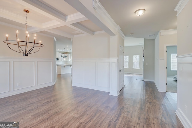 unfurnished living room featuring an inviting chandelier, a decorative wall, beam ceiling, and wood finished floors