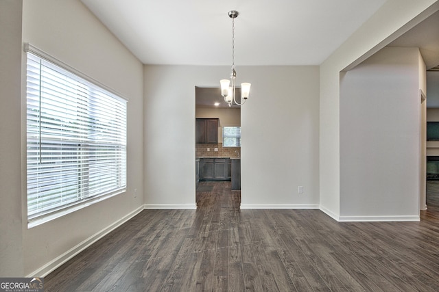 unfurnished dining area with an inviting chandelier and dark wood-type flooring