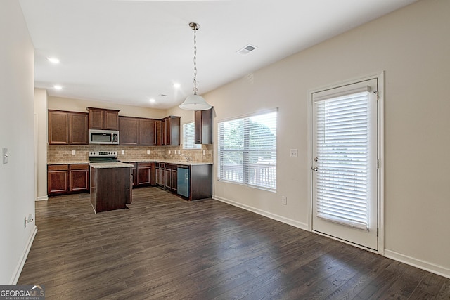 kitchen with appliances with stainless steel finishes, decorative backsplash, hanging light fixtures, a center island, and dark brown cabinets