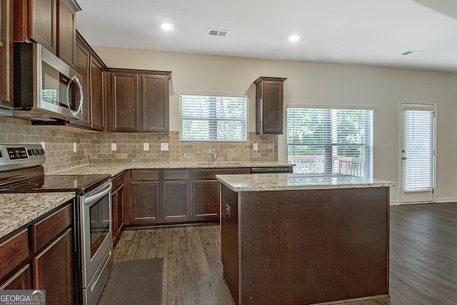 kitchen featuring light stone counters, stainless steel appliances, sink, and a kitchen island