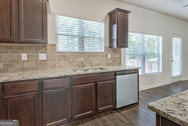 kitchen featuring dark brown cabinetry, sink, stainless steel dishwasher, light stone countertops, and backsplash