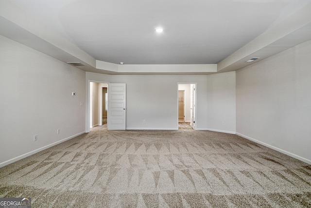 empty room with light carpet and a tray ceiling