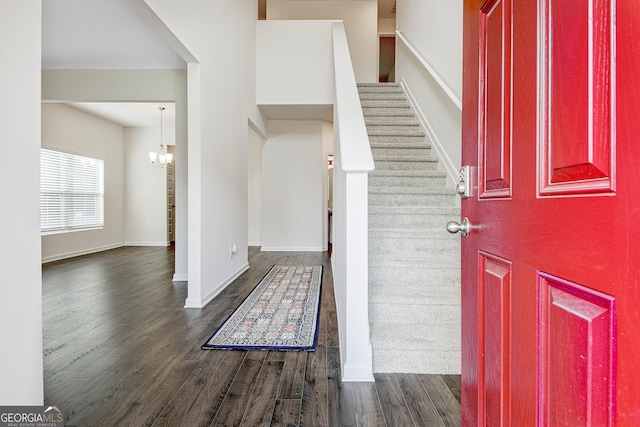 foyer entrance with an inviting chandelier and dark wood-type flooring