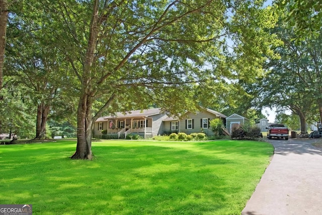 ranch-style home featuring covered porch and a front lawn