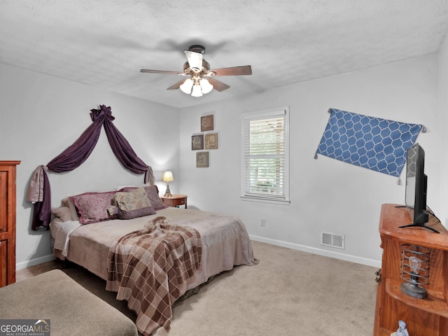 bedroom with visible vents, a ceiling fan, light carpet, a textured ceiling, and baseboards