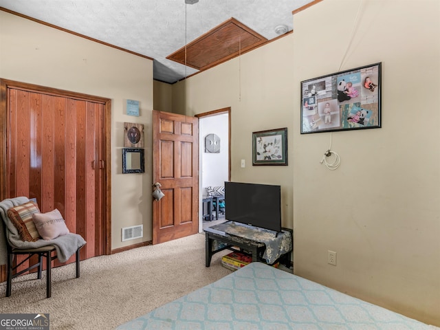 carpeted bedroom featuring attic access, visible vents, and a textured ceiling