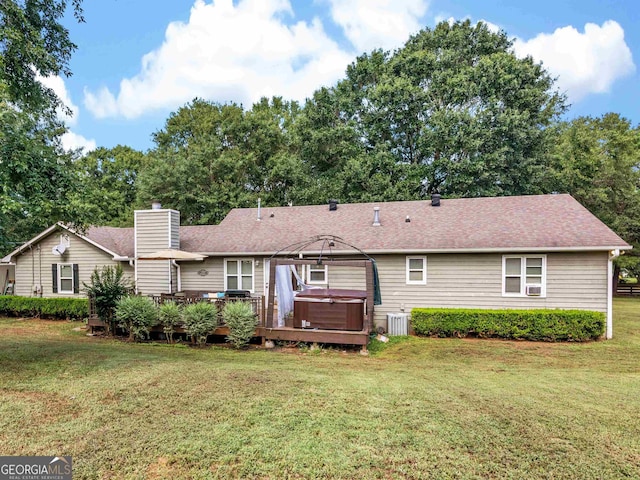 rear view of house featuring a hot tub, a lawn, central AC, and a wooden deck