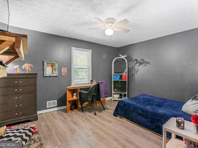 bedroom with a textured ceiling, light hardwood / wood-style flooring, and ceiling fan